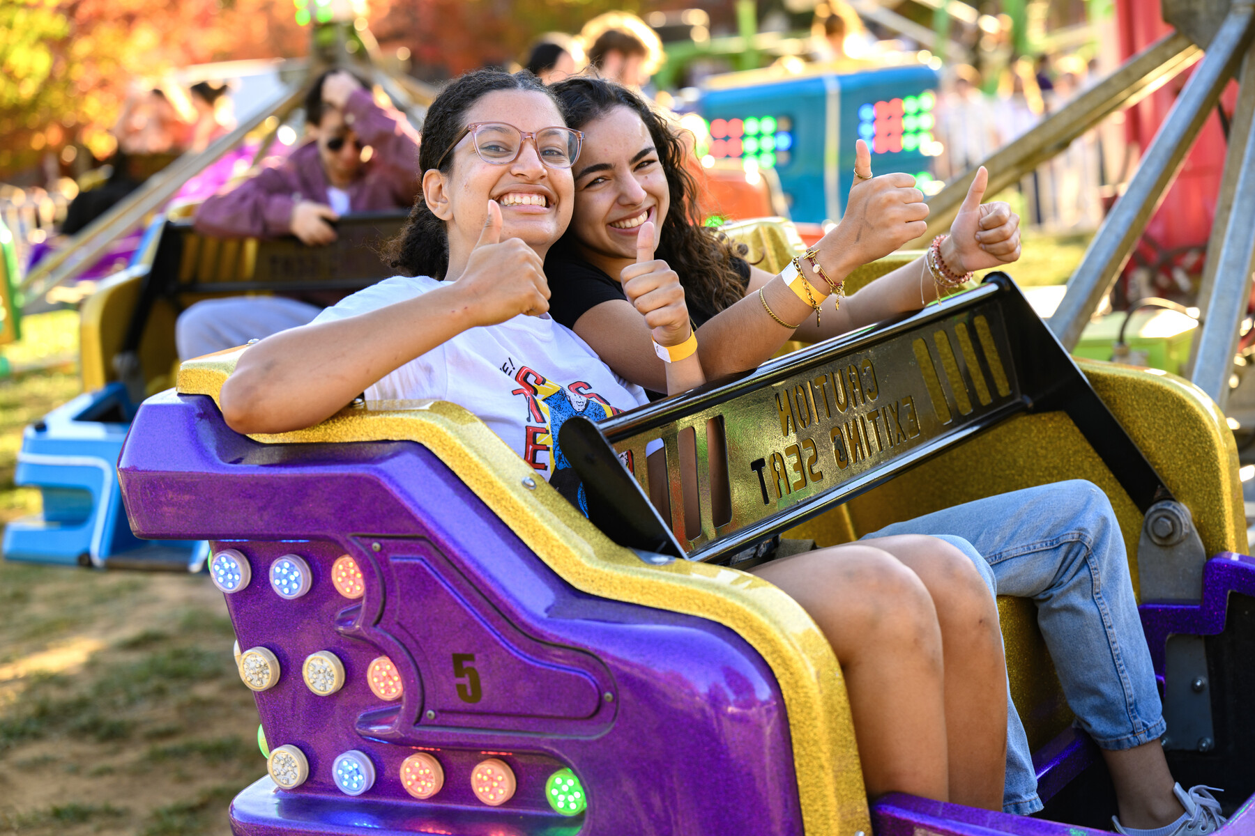 Students smiling and giving a thumbs up on homecoming carnival ride