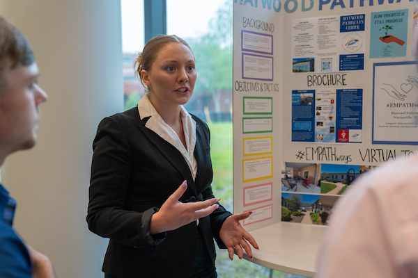 Woman communicating with group of people about project done within the communication program