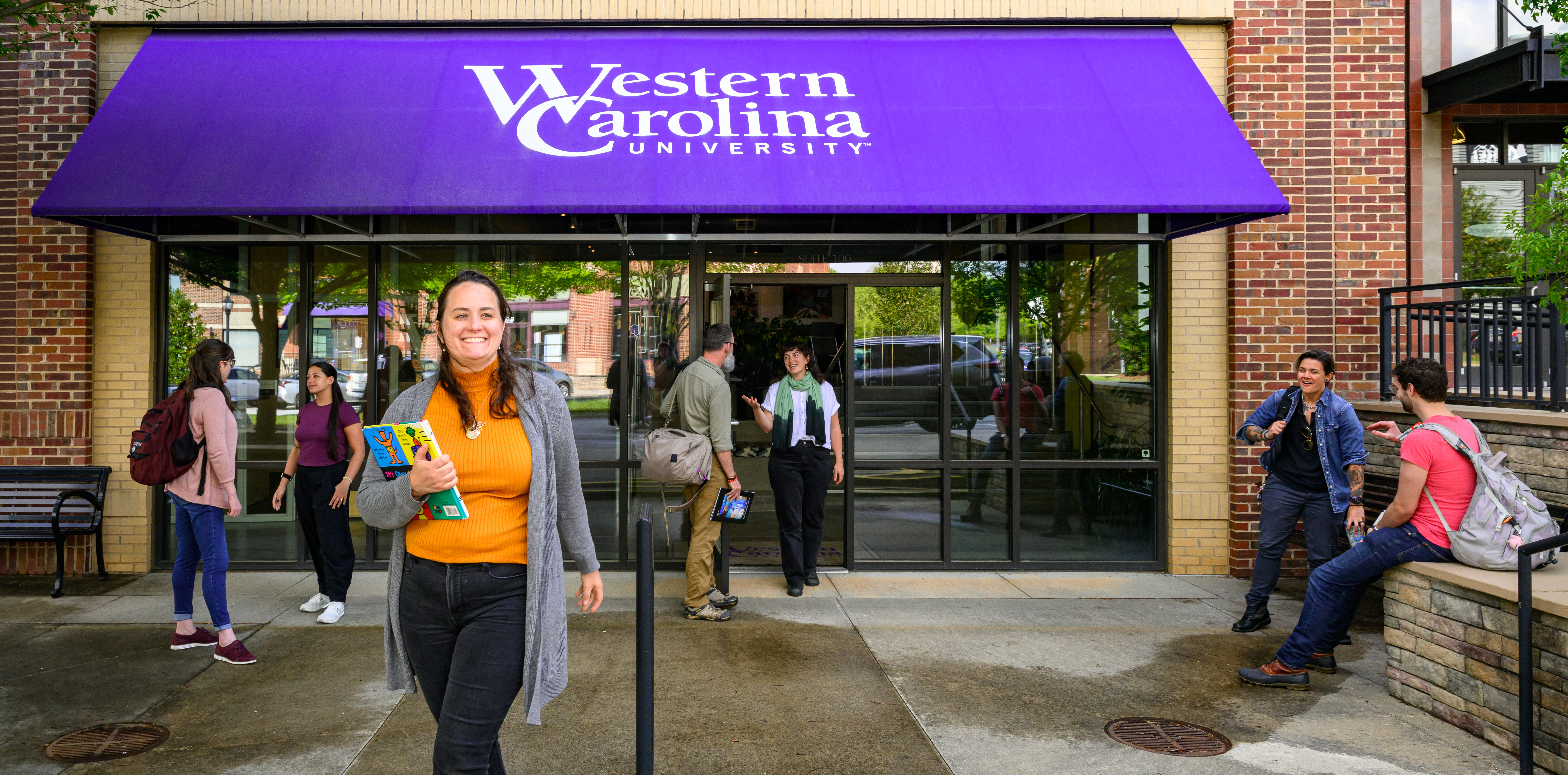 Graduate students stand talking outside of the WCU instructional entrance in Asheville