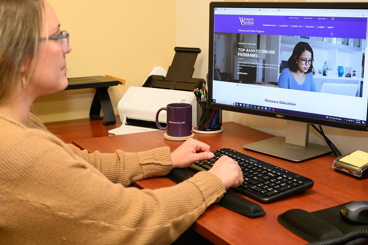 Female on computer looking at the wcu website online and distance programs page