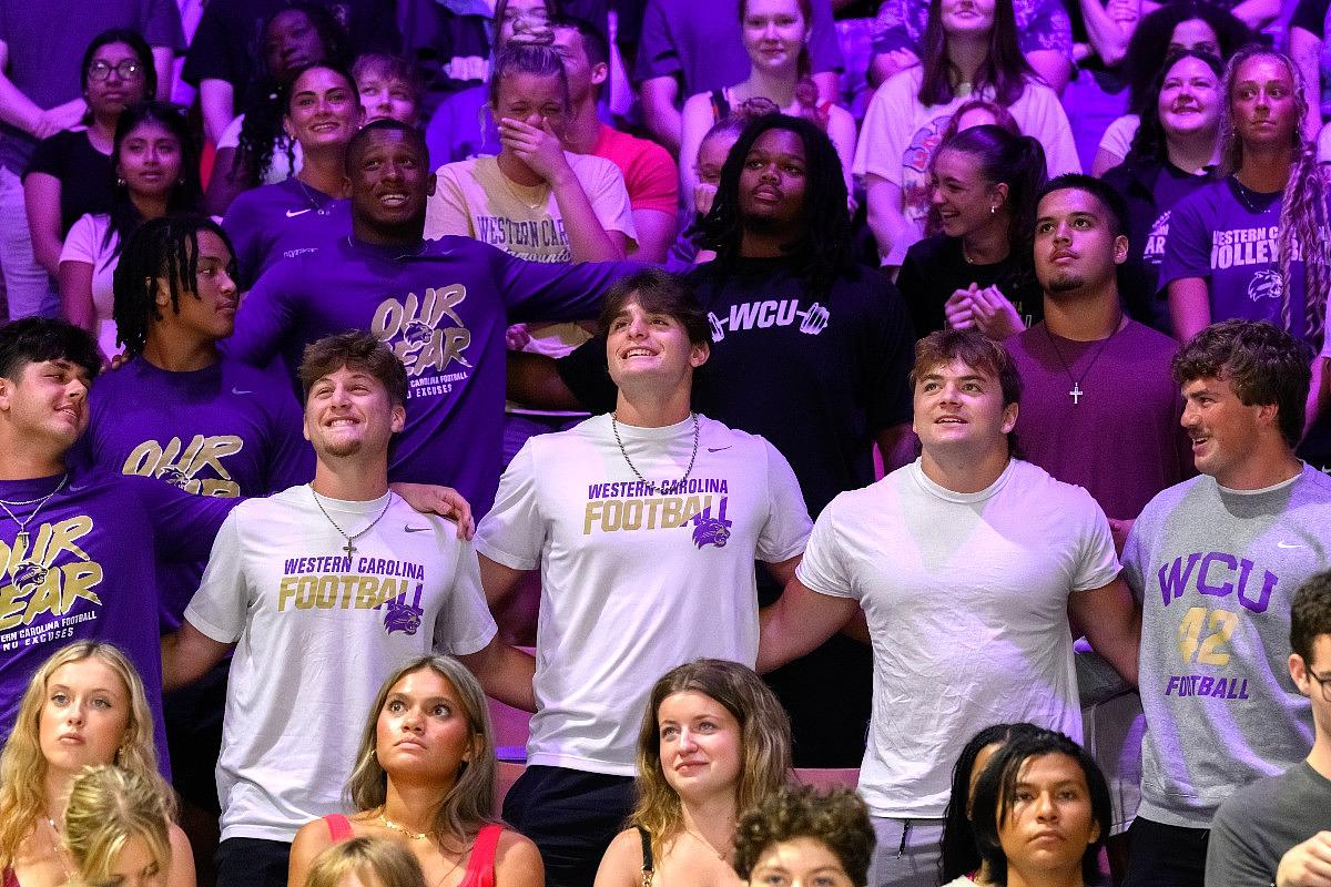 Group of Western Carolina University football fans wearing purple and white team apparel at stadium event.