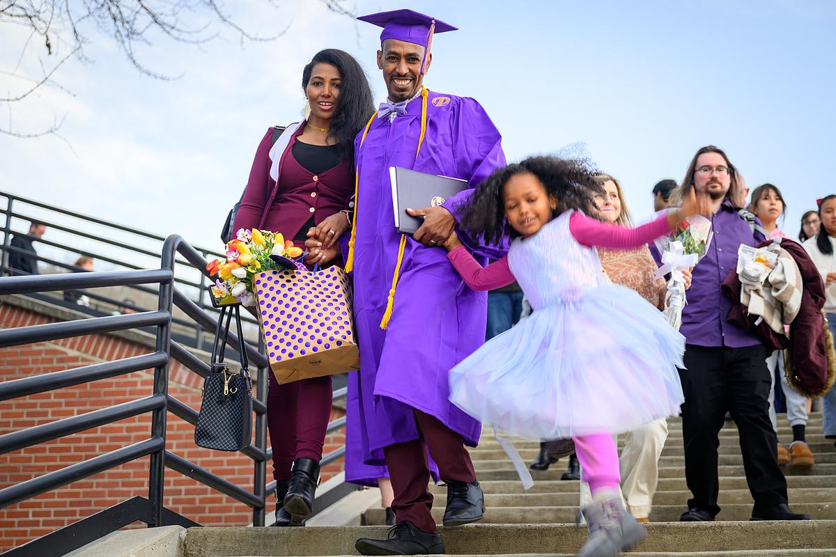 Graduate walking down stairs with their family after walking the stage