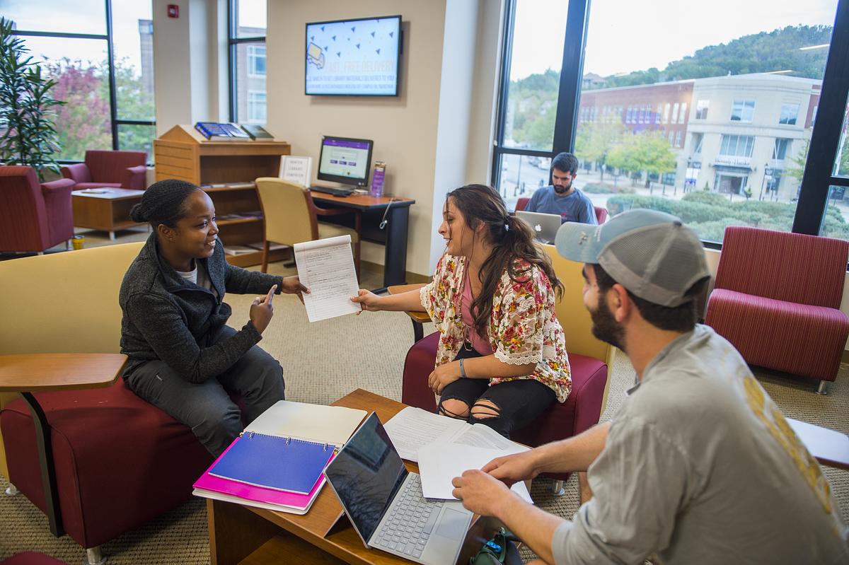 Students sitting in a lounge at the WCU Asheville location talking together.