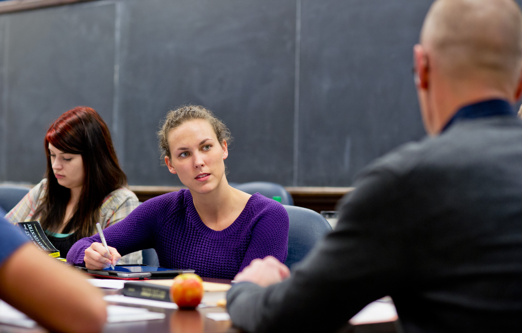 Student listens to professor at a table and takes notes